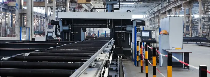 Factory floor with a long conveyor system and large processing machine, safety barriers, and control panel visible in the background.