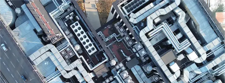 Aerial view of a city rooftop with numerous HVAC units and metal ductwork.