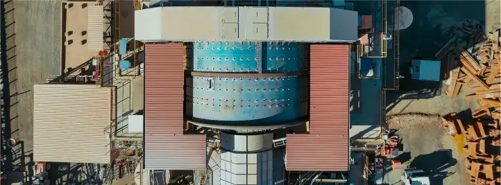 Aerial view of an industrial facility with a large blue cylindrical reactor and red catwalks.