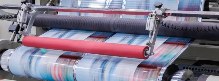 Wide-format printer rolls colorful fabric through rollers during production.